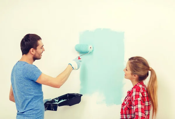 Pareja sonriente pintando la pared en casa —  Fotos de Stock