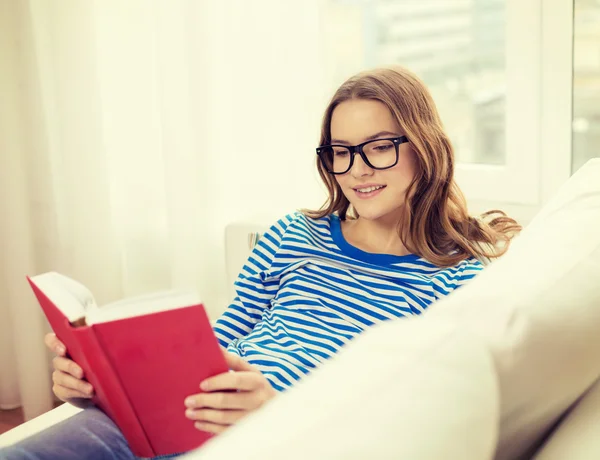 Lächelndes Teenager-Mädchen liest Buch auf Couch — Stockfoto