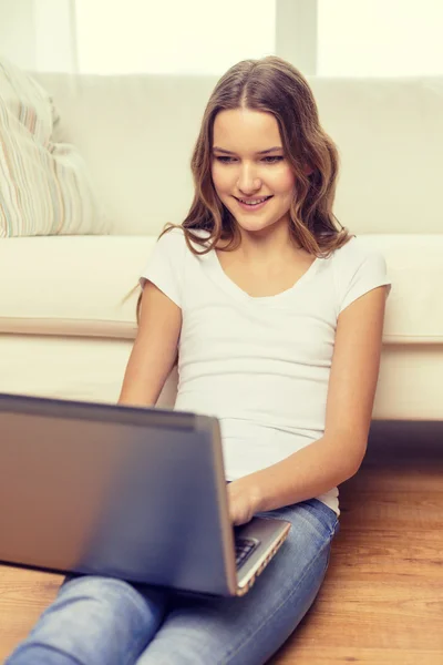 Sonriente adolescente con ordenador portátil en casa — Foto de Stock