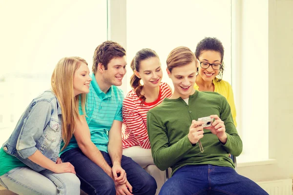 Studenti sorridenti con fotocamera digitale a scuola — Foto Stock