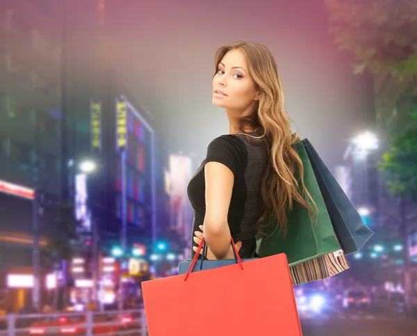 Alışveriş torbaları üzerinde şehir olan mutlu kadın — Stok fotoğraf