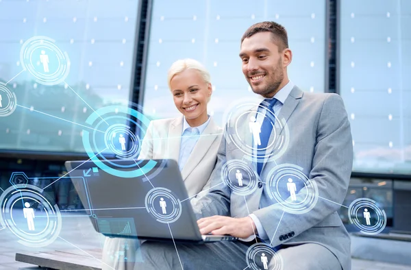 Glimlachende zakenmensen met laptop outdoors — Stockfoto