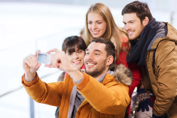 Amis heureux avec caméra sur patinoire — Photo