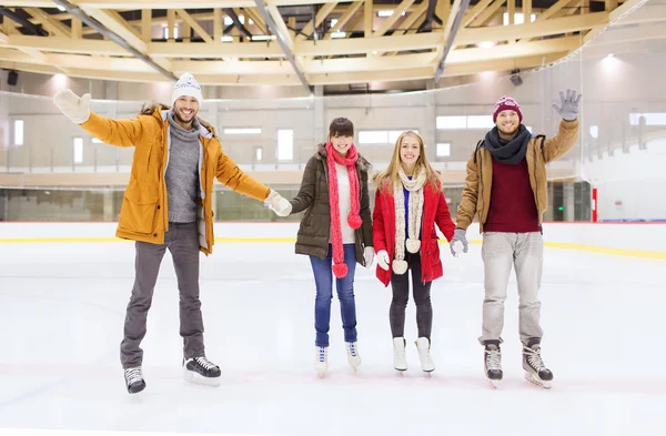 Happy friends waving hands on skating rink — Stock Photo, Image