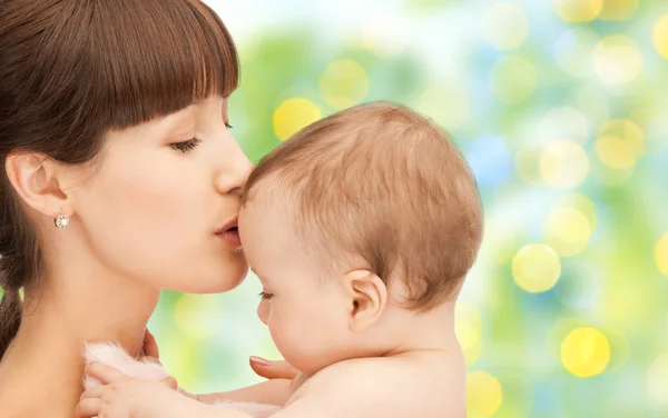 Mãe feliz com bebê sobre fundo verde — Fotografia de Stock