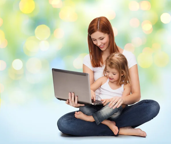 Счастливая мать с очаровательной маленькой девочкой и ноутбуком — стоковое фото