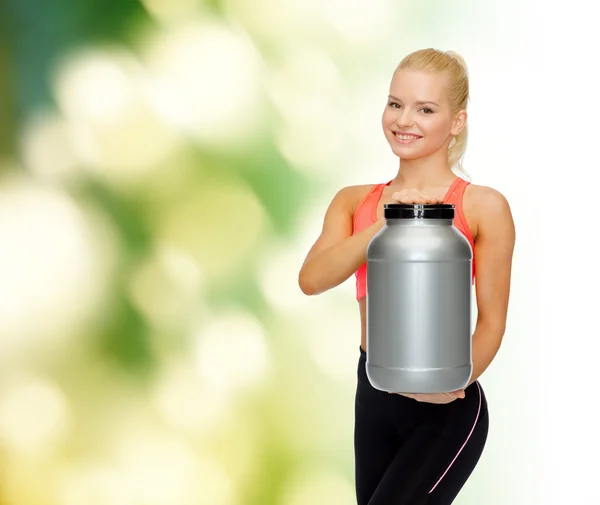 Mujer deportiva sonriente con tarro de proteína — Foto de Stock