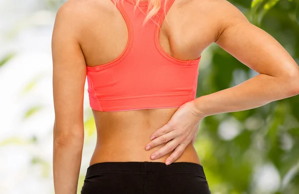 Крупным планом спортивная женщина, касающаяся своей спины — стоковое фото