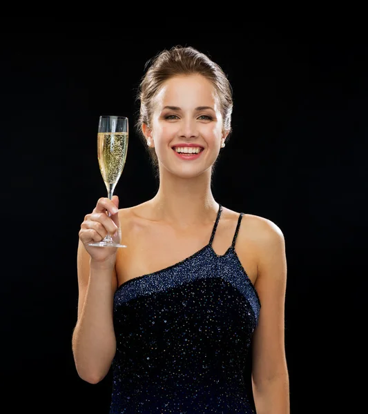 Sonriente mujer sosteniendo un vaso de vino espumoso —  Fotos de Stock