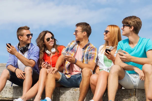 Группа улыбающихся друзей со смартфонами на открытом воздухе — стоковое фото
