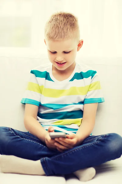 Lachende jongetje met smartphone thuis — Stockfoto