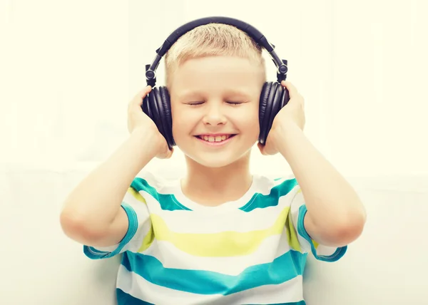 Petit garçon souriant avec écouteurs à la maison — Photo