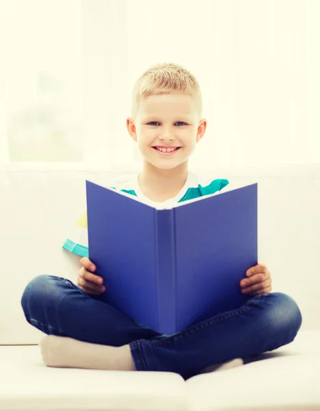 Sourire petit garçon lecture livre sur canapé — Photo