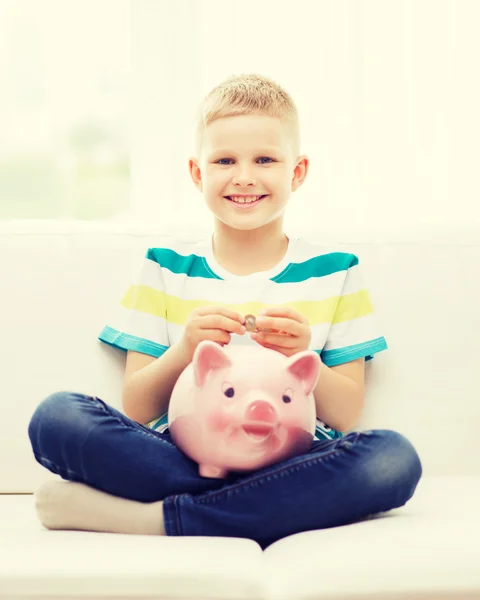 Garotinho sorridente com banco porquinho e dinheiro — Fotografia de Stock