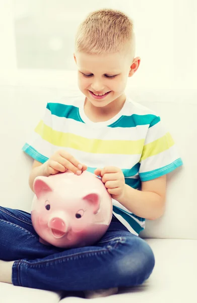 Garotinho sorridente com banco porquinho e dinheiro — Fotografia de Stock