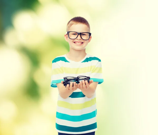 Sorridente ragazzo in occhiali tenendo gli occhiali — Foto Stock