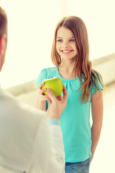 Manliga läkare ger ett äpple till leende liten flicka — Stockfoto