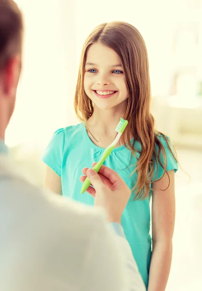 Médico masculino dando cepillo de dientes a la chica sonriente —  Fotos de Stock