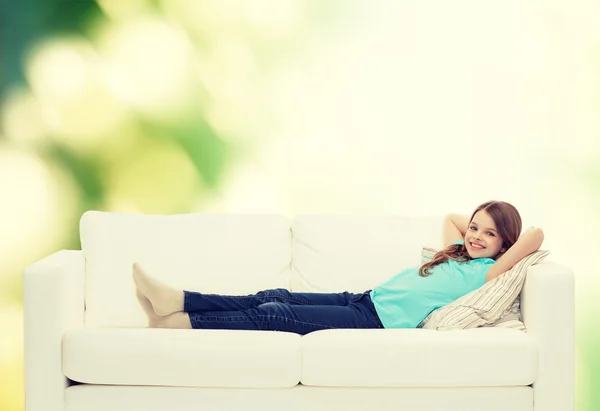 Lächelndes kleines Mädchen auf Sofa liegend — Stockfoto