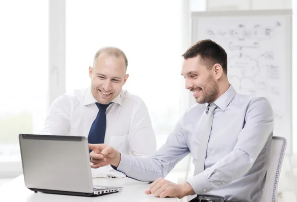 Two smiling businessmen with laptop in office — Stock Photo, Image