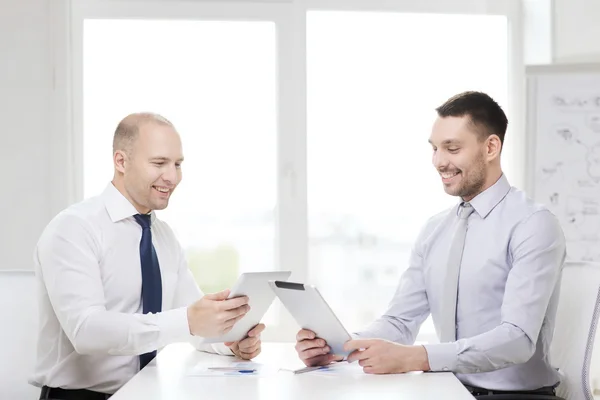Два усміхнені бізнесмени з планшетним ПК в офісі — стокове фото