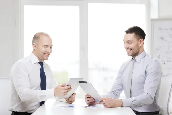 Twee Glimlachende zakenmensen met tablet pc in office — Stockfoto