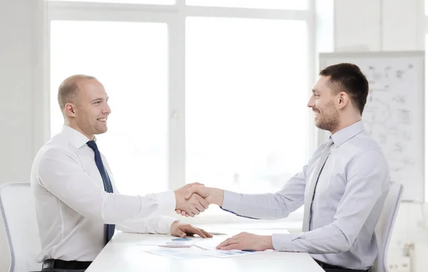 Dois empresários sorridentes apertando as mãos no escritório — Fotografia de Stock