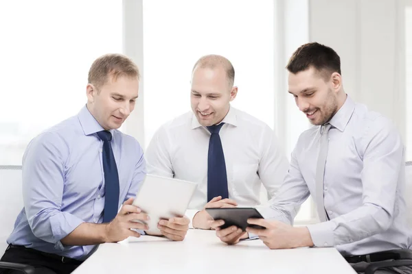 Три улыбающихся бизнесмена с планшетным ПК в офисе — стоковое фото