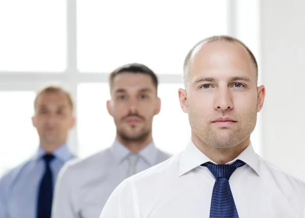 Homme d'affaires sérieux au bureau avec l'équipe sur le dos — Photo