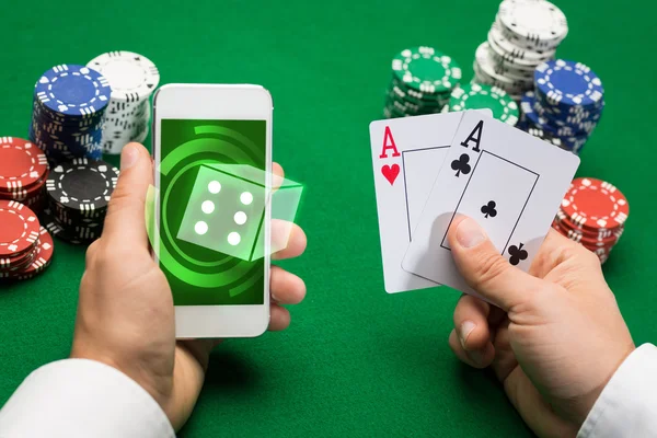 Jugador de casino con tarjetas, smartphone y fichas —  Fotos de Stock