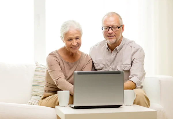 Happy senior couple with laptop and cups at home — Stock Photo, Image