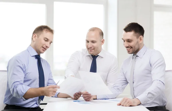 Hombres de negocios sonrientes con papeles en la oficina — Foto de Stock