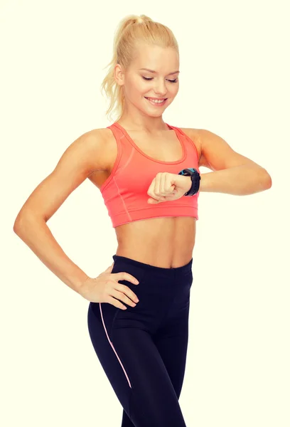 Smiling woman with heart rate monitor on hand — Stock Photo, Image