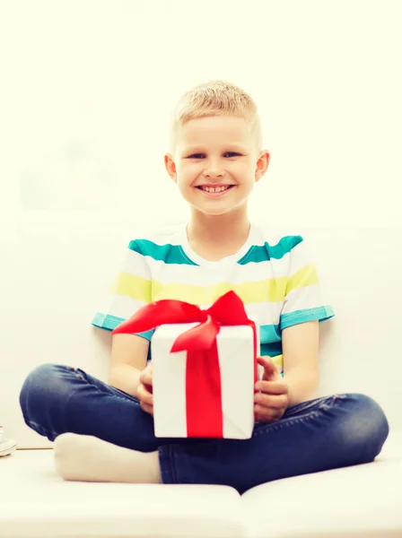 Lächelnd kleine Geschenkschachtel auf Couch sitzend — Stockfoto