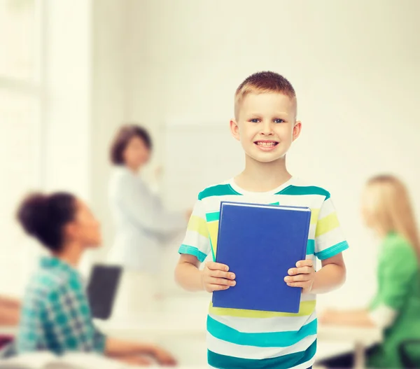 Sorridente piccolo studente ragazzo con libro blu — Foto Stock