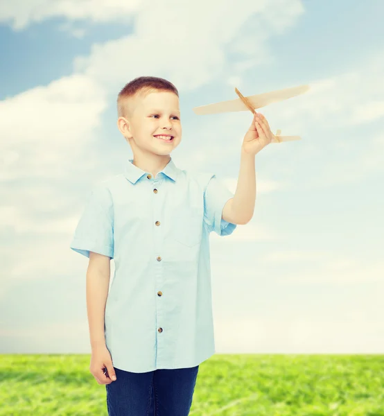 Улыбающийся мальчик с деревянной моделью самолета — стоковое фото
