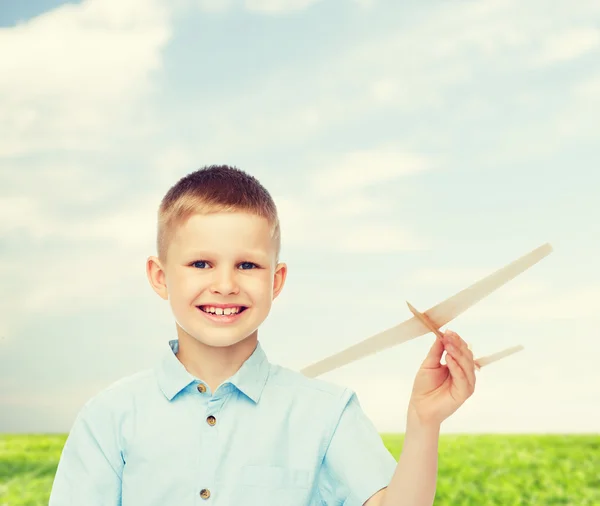 Smiling little boy holding a wooden airplane model — Stock Photo, Image