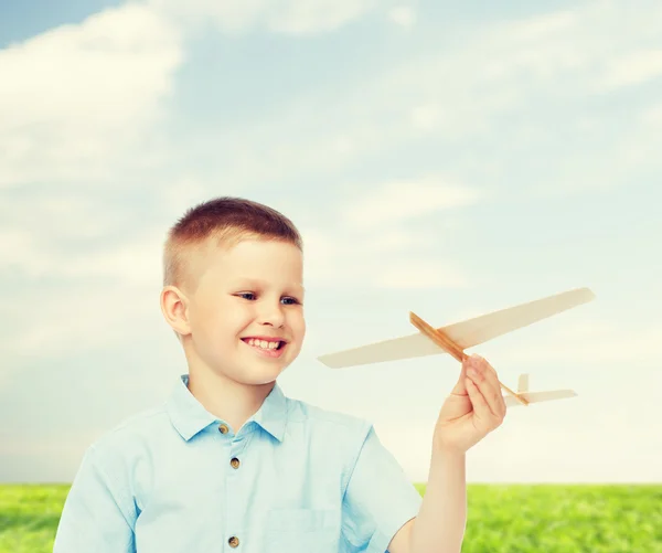 Niño sonriente sosteniendo un modelo de avión de madera — Foto de Stock