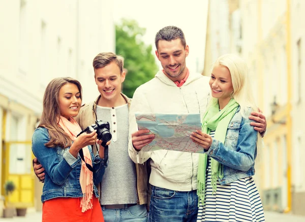 Grupo de amigos sonrientes con mapa y cámara fotográfica —  Fotos de Stock