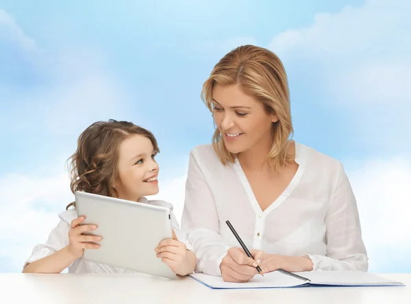 Kobieta z notebooka i dziewczynka trzymając tablet pc — Zdjęcie stockowe