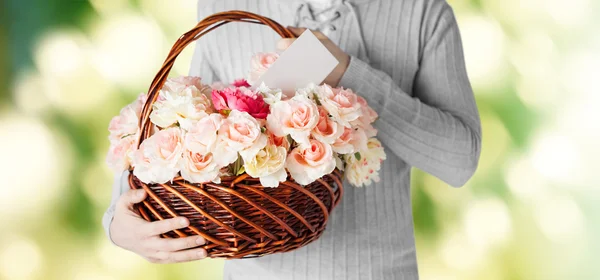 Hombre sosteniendo cesta llena de flores y postal — Foto de Stock