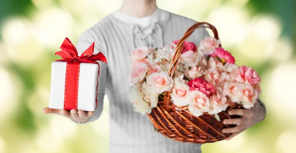 Homme tenant panier plein de fleurs et boîte cadeau — Photo