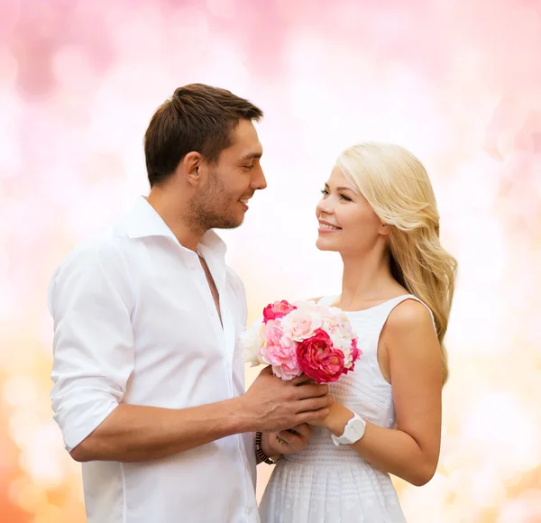 Happy couple with flowers over lights background — Stock Photo, Image
