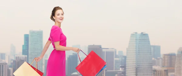 Jonge gelukkig vrouw met boodschappentassen over stad — Stockfoto