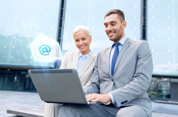 Smiling businesspeople with laptop sending e-mail — Stock Photo, Image