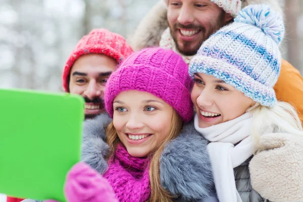 Amigos sorridentes com tablet pc na floresta de inverno — Fotografia de Stock