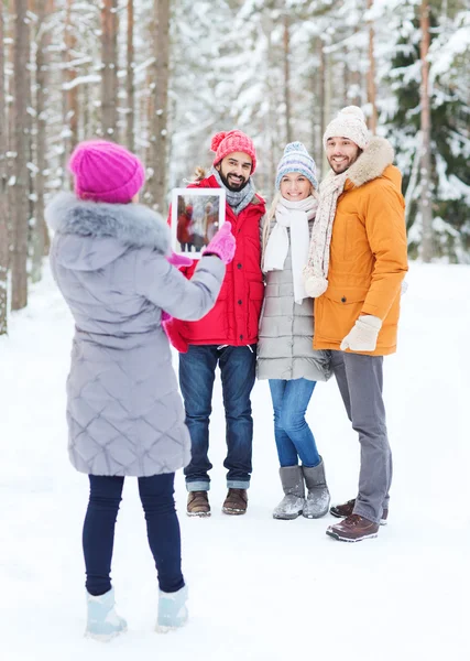 Amigos sorridentes com tablet pc na floresta de inverno — Fotografia de Stock