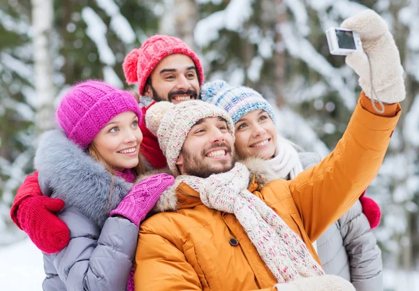 Lachende vrienden met camera in winter forest — Stockfoto