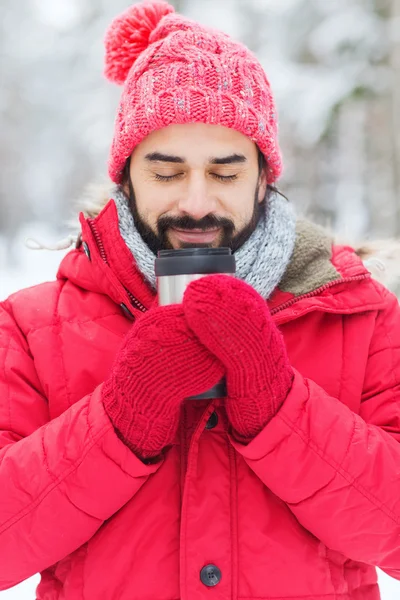 Leende ung man med cup i vinter skog — Stockfoto