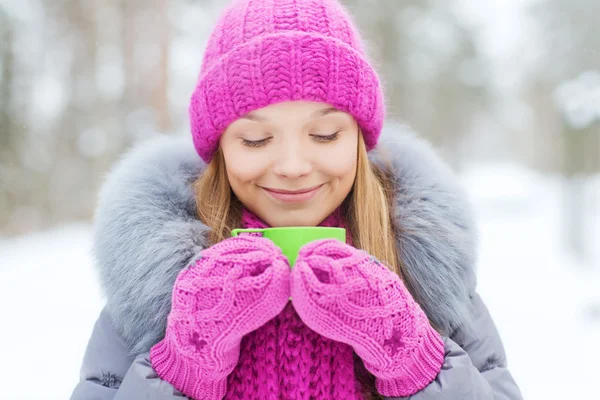 Smiling young woman with cup in winter forest — Stock Photo, Image